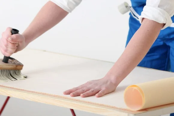 Person trägt Kleister mit Quast auf Tapete auf